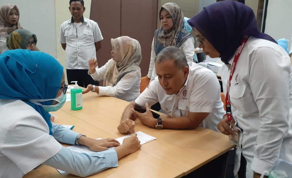 Kepala Departemen Komunikasi dan Hukum Perusahaan PT Semen Padang Oktoweri mendengar penjelasan dokter pada kegiatan vaksinasi influenza  bagi karyawan/wati di Lantai I Kantor Pusat Semen Padang, Senin (16/3)