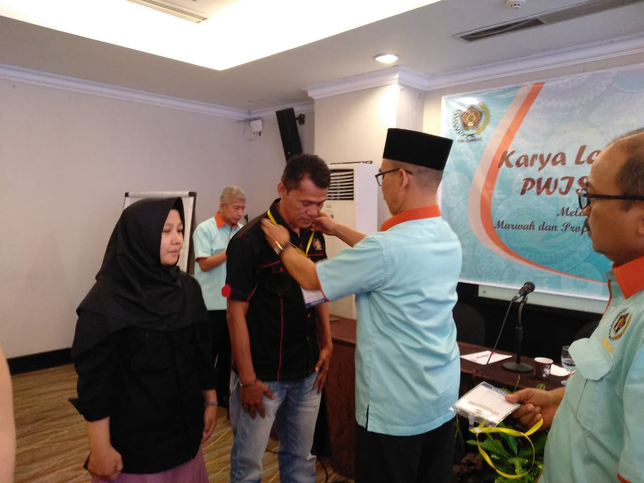 Pemasangan tanda peserta KLW oleh Ketua PWI Sumbar Heranof Firdaus