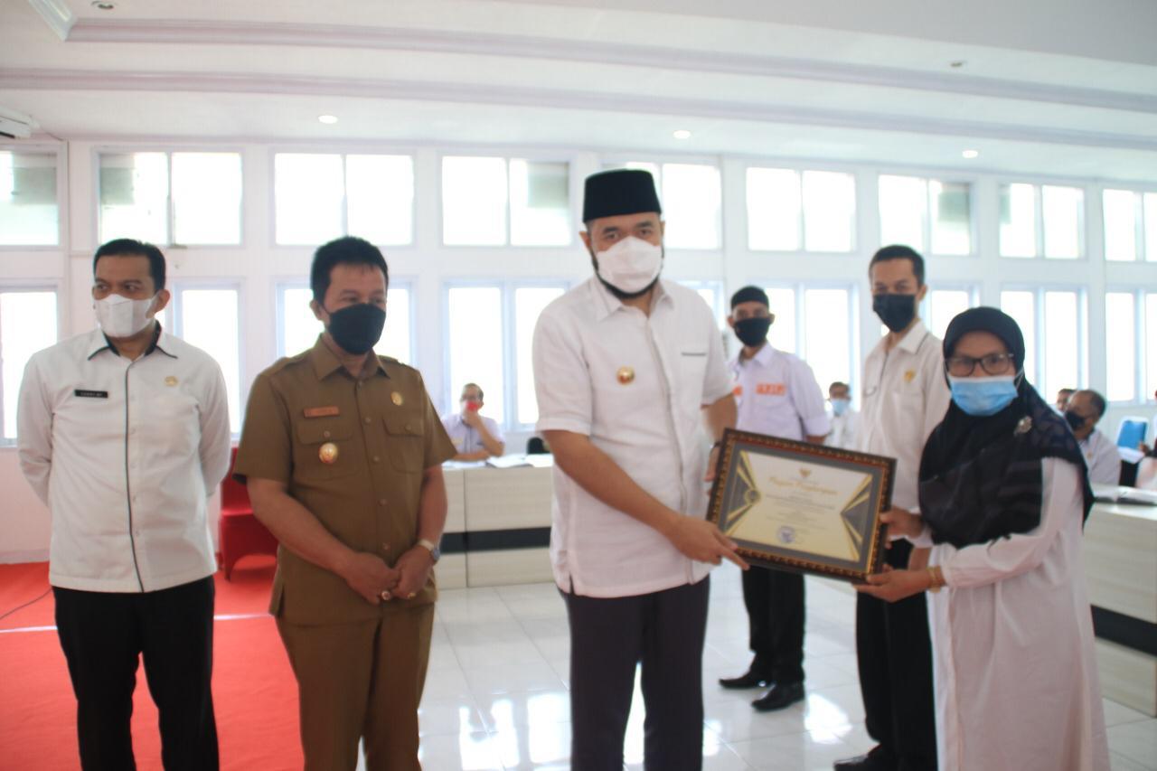 Wali Kota Fadhly Amran serahkan sertifikat Piagam OPD Terbaik 2021 pada Kadisdukcapil Padang Panjang, Dra. Maini.