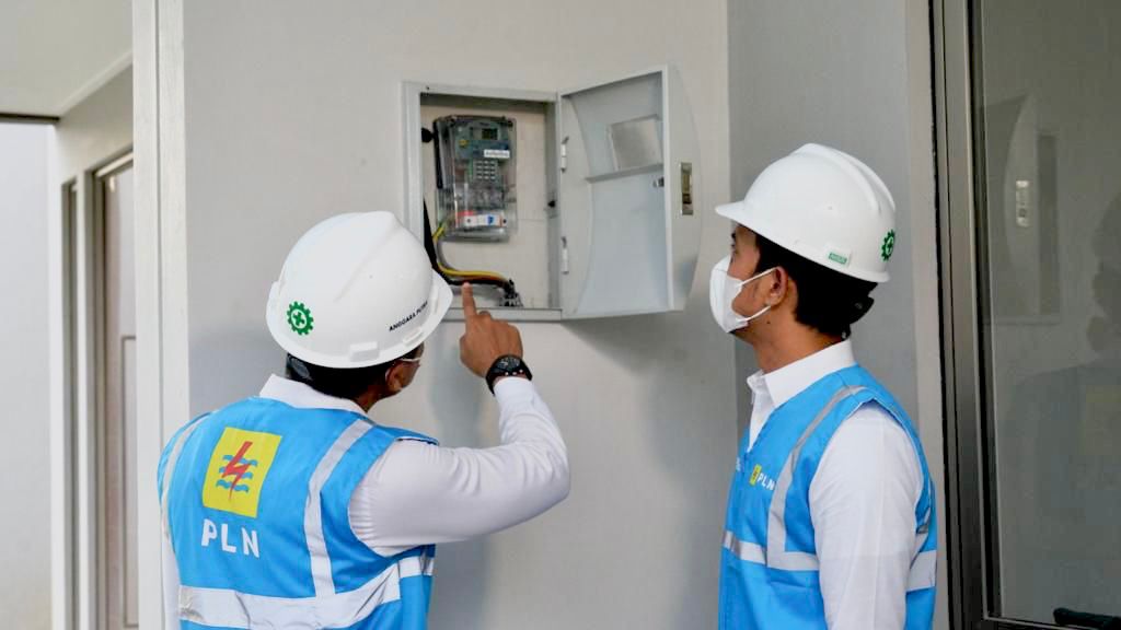 Ilustrasi petugas PLN melakukan penambahan daya pada instalasi listrik pelanggan.