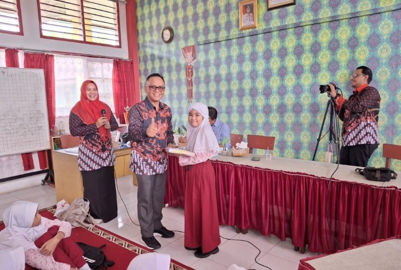 Ketua FKPT Provinsi Sumbar, Adil Mubarak menyerahkan bingkisan kepada murid SD, sebagai penulis terbaik dalam acara FKPT. Foto Gk.