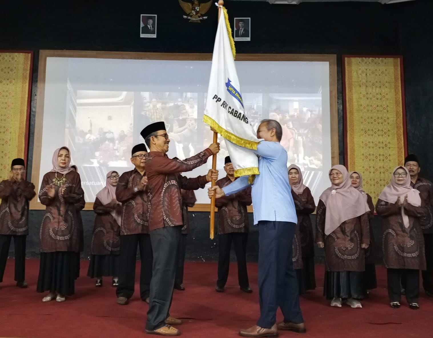 PLH Kepala LPP RRI Padang, Yusrizal, SH, MM., menyerahkan pataka Persatuan Pensiunan RRI Padang, Heranof Firdaus, saat momen pelantikan Pengurus Pensiunan RRI.Padang, Selasa (19/8/2026). Foto Diut.