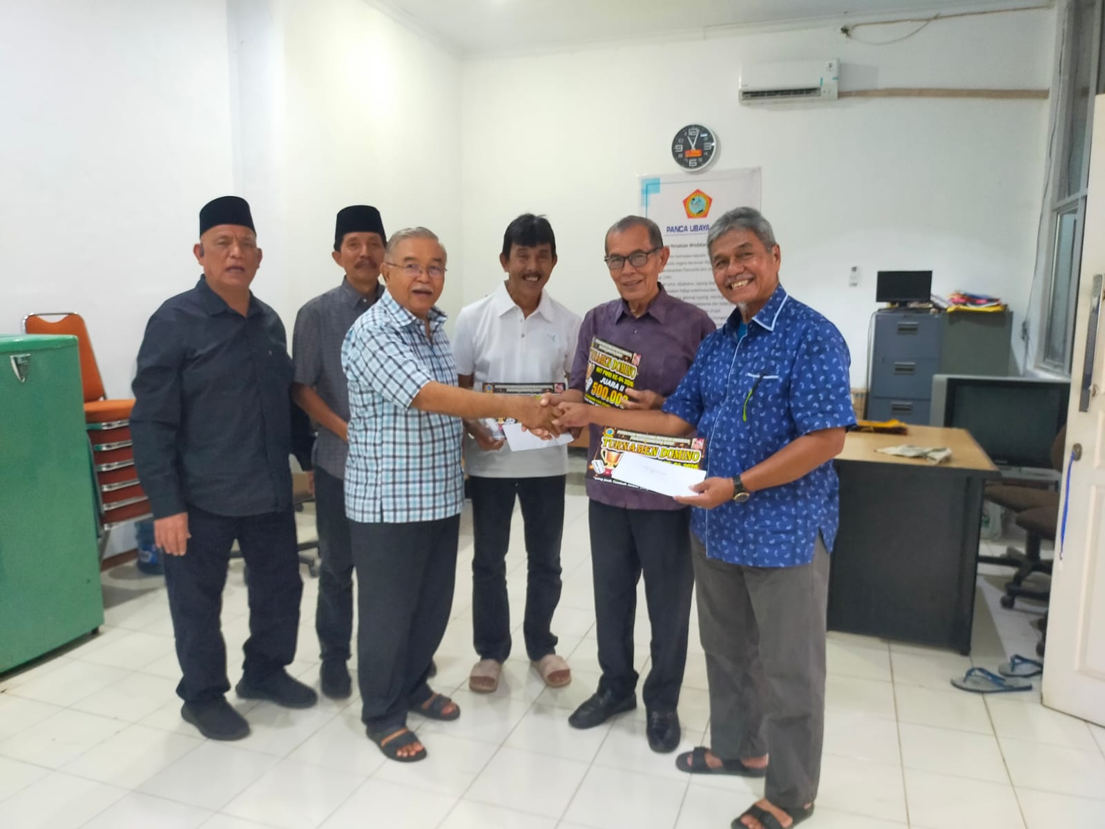 Zulnadi (kanan) dan pasangan dominonya Azharnuri menerima hadiah dari panitia Syahrial Syam di sekretariat PWRI Sumbar di Padang. Foto ist. 
