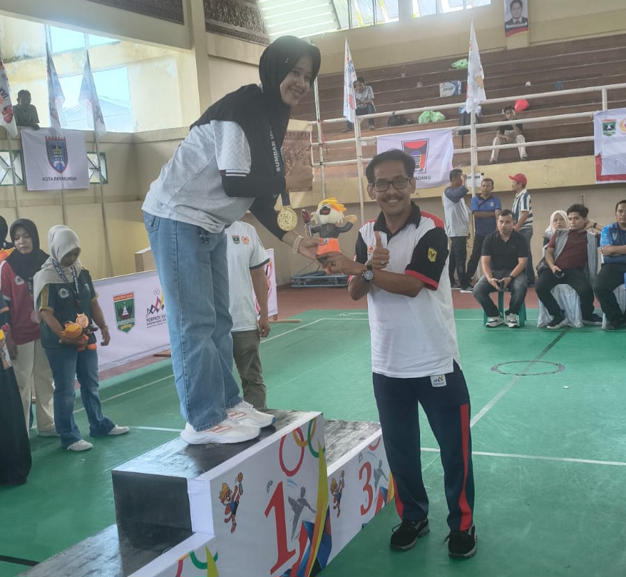 Ketua KONI Tanahdatar Novitra Kemala kalungkan medali pada atlit Tanahdatar peraih medali. (chandra antoni)