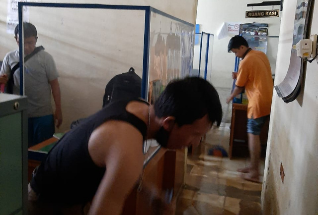 Staf Kominfo Solok membersihkan ruangan pasca banjir.