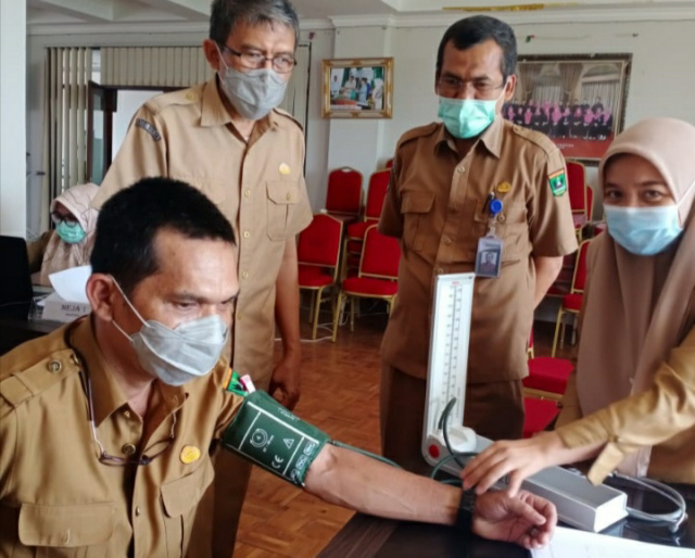 Disaksikan Direktur RSMN drg Basyir Busnia (berdiri, tengah), dan Wadir Keuangan RSMN, Yopi Oktavia (berdiri, kiri), seorang nakes RSMN, Endri Joni tengah diukur tensinya sebelum divaksinasi.