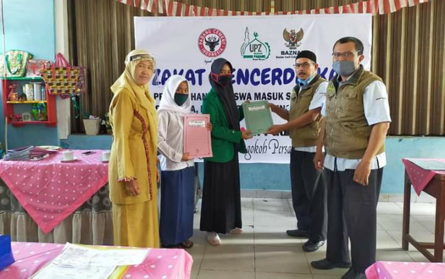 Kepala Pelaksana Harian UPZ Baznas Semen Padang Muhammad Arif (dua dari kanan) menyerahkan bantuan pendidikan secara simbolis kepada perwakilan siswa di Kota Padang
