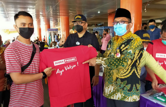 Plt Walikota Padang Hendri Septa (kanan) menyerahkan kaos bertuliskan Ayo Vaksin! dari Semen Padang kepada pedagang.