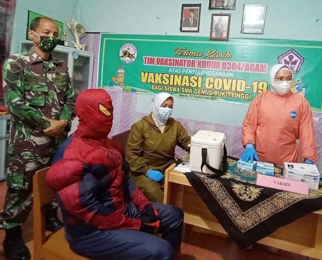 Kepala SMK Genus Bukittinggi Defi Endri mengenakan pakaian ala Spiderman saat divaksin
