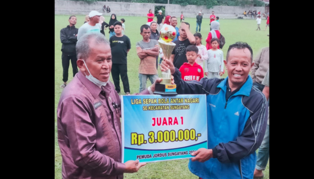 Kadis PMDPPKB Drs. Novenril menyerahkan tropi bergilir, tropi tetap serta uang tunai pada kapten Chandra Antoni.