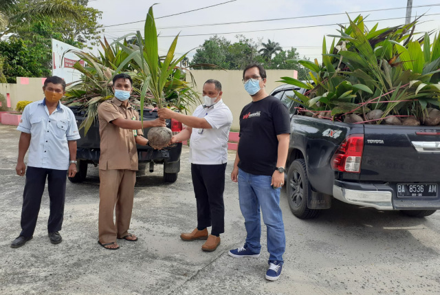 Staf Health Safety Environment (HSE) PT Semen Padang Alif Yuza secara simbolis serahkan bibit kepada Plt Kabid Perkebunan Dinas Pertanian Kabupaten Dharmasraya Ijhon