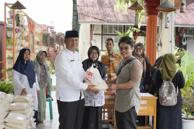 Ketua PGRI Kota Padang Panjang Drs. Afrizal saat serahkan paket sembako pada salah seorang guru, Rabu (27/4/2022) siang.