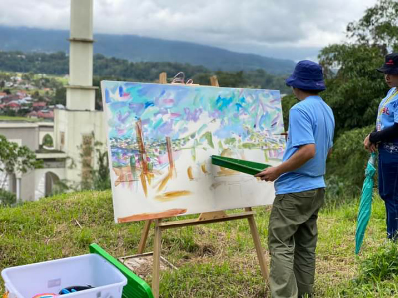 Salah seorang seniman lukis terlihat tengah melukis komplek Islamic Centre.