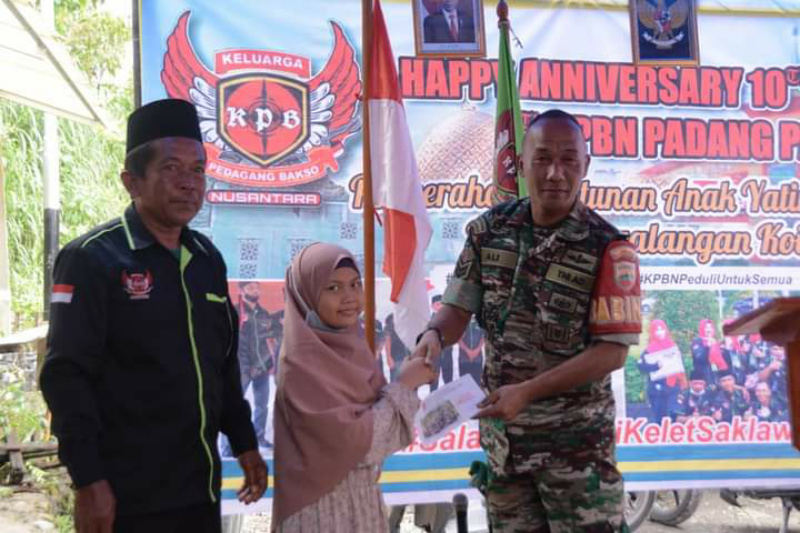 Pengurus KPBN saat serahkan bantuan pada salah seorang anak yatim.