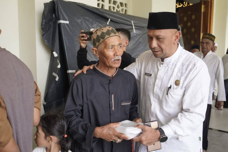 Asisten, I Putu Venda saat serahkan nasi kotak pada salah seorang jamaah usai sholat Jumat di Masjid Manarul Ilmi.