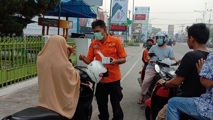 Anggota BPBD Kota Solok membagikan masker kepada pengendara motor guna mencegah dampak kabut asap yang makin tebal